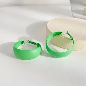 Vibrant green matte C-shaped geometric hoop earrings shown on a minimalist wooden stand