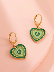 Detailed close-up of green heart enamel earrings with gold metallic borders on a tray