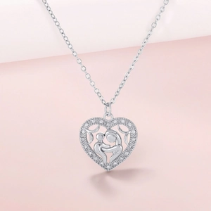 Detail of silver heart necklace with mother and child silhouette and sparkling zircons