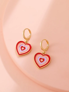 Macro detail of heart-shaped multi-color enamel dangle earrings on a pink pedestal