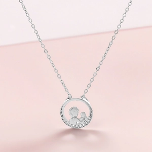 Macro detail of silver necklace featuring a mother and child pendant with white zircons