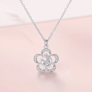 Close-up of silver flower necklace with mother and child pendant and clear zircons