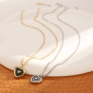 Detail of heart pendants with black enamel inlay in gold and silver finishes