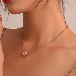 Primo piano della collana con pendente H in oro rosa e cristalli pavé su una modella