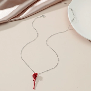 Detailed view of red rose pendant with silver chain on soft satin background