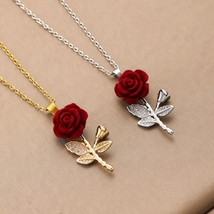 Detailed macro view of red velvet rose pendant with zircon leaves in gold and silver