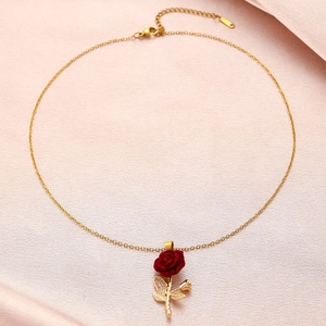 Close-up of a 3D red rose flower pendant on a gold necklace with detailed green leaves