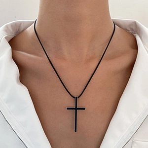 Detailed view of a black cross pendant necklace with silver edges on a white shirt