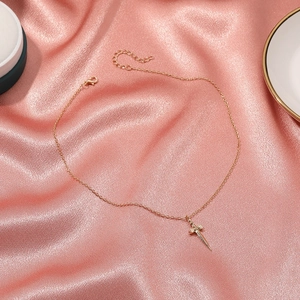 Dettaglio di una collana con ciondolo a spada dorata con cristalli su seta rosa