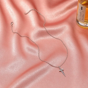 Dettaglio del ciondolo a forma di spada vintage su catena d'argento su seta rosa
