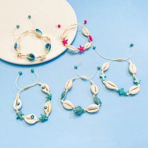 Set di braccialetti fatti a mano con conchiglie e stella marina su sfondo blu chiaro