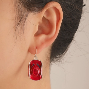 Close-up of red resin cowboy hat pendant earrings with silver hooks for women