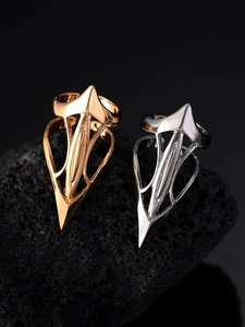 Macro detail of gold and silver gothic punk claw rings on black volcanic stone