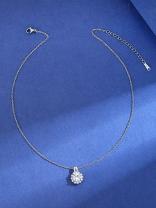 Detail of silver necklace with round zircon floral pendant on navy textured background