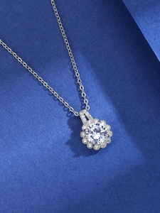 Macro shot of silver six-prong cubic zirconia sunflower pendant on navy background