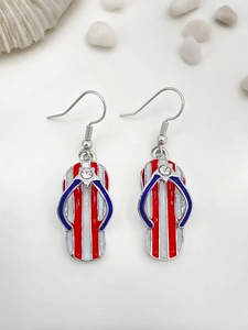 Close-up of red, white and blue flip-flop earrings with rhinestones on summer beach props