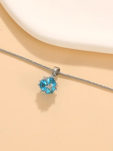 Detail of four-facet light blue crystal pendant with silver claw setting on snake chain