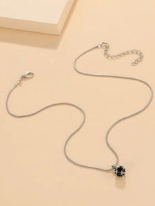 Detail of silver snake chain necklace featuring a black spherical zircon pendant in claw setting