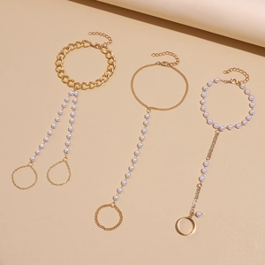 Detail of bohemian gold-plated chain bracelet with rings and white faux pearls
