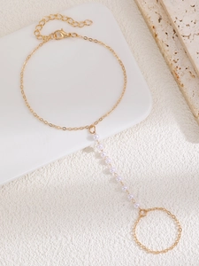 Macro view of gold hand harness featuring delicate imitation pearls and adjustable chain