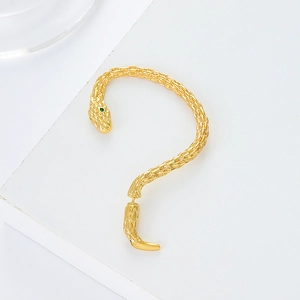 Détail macro du耳 clip serpent doré avec texture écailles et pierre précieuse verte