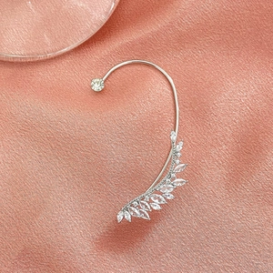 Close-up of leaf shaped silver ear cuff with marquise zircons on silk background