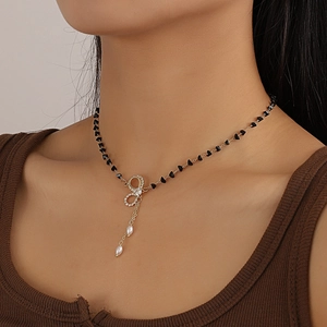 Girocollo boho con perline nere, ciondolo a fiocco dorato e nappa di perle su modella