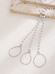 Detail view of multi-layer pearl finger bracelet with silver chains and white beads