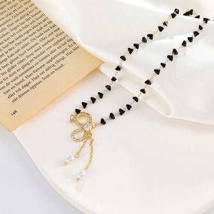 Collana elegante con ciondolo a fiocco in zirconi e perle a goccia su sfondo di seta bianca