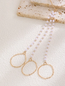 Detailed close-up of golden multi-layered finger bracelet with delicate white pearls