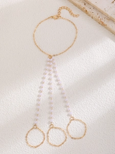 Detailed close-up of a golden multi-layer pearl slave bracelet with three finger rings