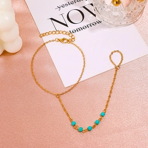 Detail of golden bohemian slave bracelet with turquoise beads on pink silk background