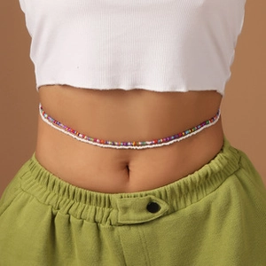 Détail de la chaîne de taille perlée colorée et du rang de perles blanches sur le mannequin