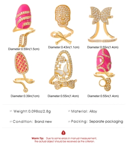 Detailed grid of six gold-plated nail rings featuring enamel, butterfly, and skull motifs