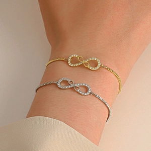 Detail of infinity charm bracelet with micro-pave cubic zirconia on gold and silver chain