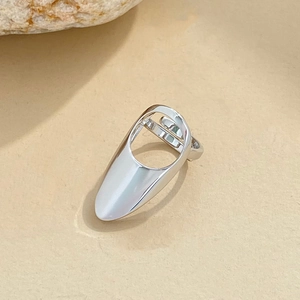 Macro detail of a silver adjustable nail ring with rhinestones on a natural rock background