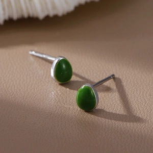 Boucles d'oreilles minimalistes en pierre verte et base argentée sur fond élégant