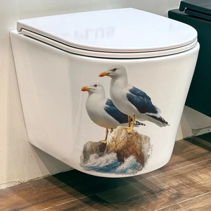 Modern white wall-mounted toilet with creative seagull on rock sea-themed wall sticker