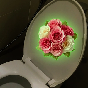 Luminous floral wall sticker with pink and white roses on a toilet lid in the dark