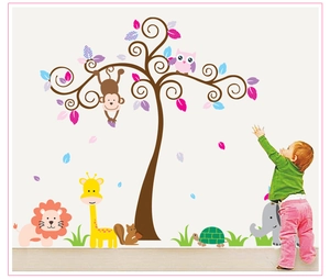 Toddler touching colorful cartoon tree wall decals with owl and safari animals