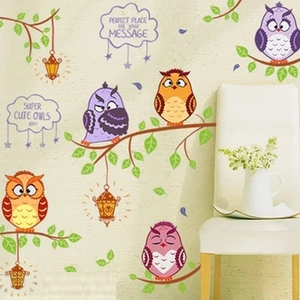Detail of cartoon owls and tree branches wall stickers with clouds on a yellow wall