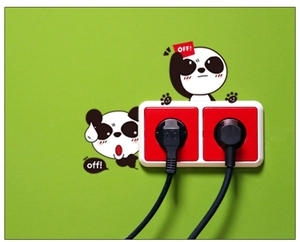 Détail de stickers muraux panda avec signe 'OFF!' sur prise sur un fond de mur vert clair