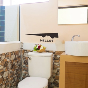 Close-up of a funny black monster silhouette wall sticker with HELLO text on a bathroom wall