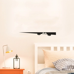 Close-up of creative peeking eyes wall sticker on smooth wall in bedroom setting