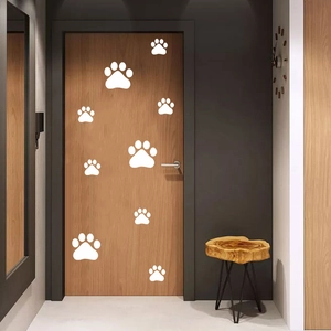Detail view of white dog paw print stickers applied on a modern wooden door surface