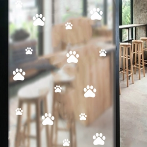 Detail of white paw print decals in various sizes applied on a frosted glass window surface