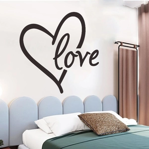 Detail of black 'Love' wall sticker with heart design above a bed in a modern bedroom