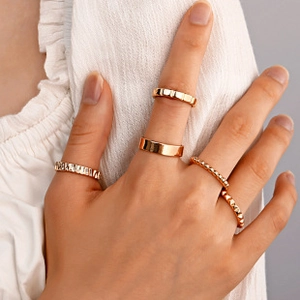 Close-up of a 5-piece gold ring set featuring heart and butterfly cutout textures