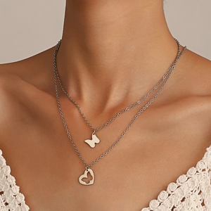 Close-up of double layered silver necklace with butterfly and hollow heart pendants