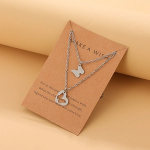 Detail of stainless steel double-layer necklace with butterfly and heart charms on a card